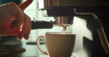 Kahve makinesinden fincana kahve dökülüyor. Ev yapımı sıcak Espresso. Filtre tutacağı kullanılıyor. Taze kahve akıyor. Sabahları kavrulmuş sade kahve içmek..