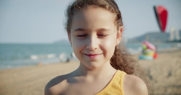 Портрет Смішна дівчинка усміхнена дитина дивиться на камеру весела насолоджуючись теплими літніми канікулами на узбережжі набережної повільний рух, мила дитина з гарним обличчям. Концепція щасливе дитинство — стокове відео