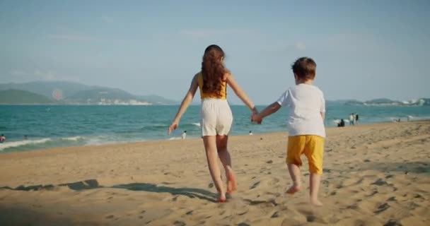 Щасливі маленькі діти біжать по пляжу, граючи зі своїм собакою, сімейні пляжні канікули — стокове відео