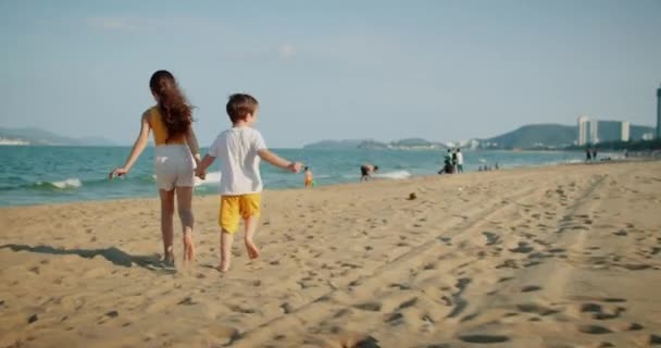 Çocuklar sahilde koşuyor. Mutlu beyaz çocuklar gülümsüyor sahilde köpekleriyle koşuyorlar, aile tatillerinde oynuyorlar. Portre gülüşleri güzel kardeşlere benziyor. Küçük çocukların plaj tatili kavramı — Stok video