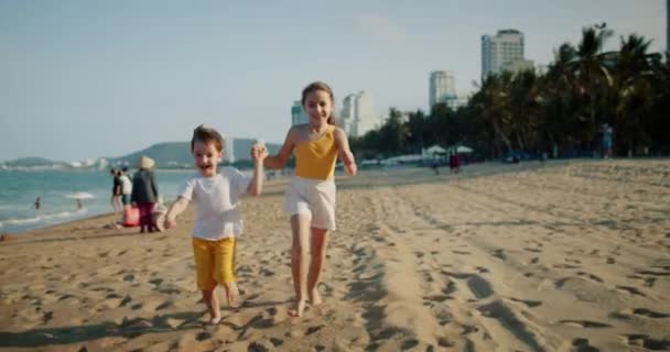 Szczęśliwe młode dzieci biegające po plaży bawiące się z psem, rodzinne wakacje na plaży — Wideo stockowe