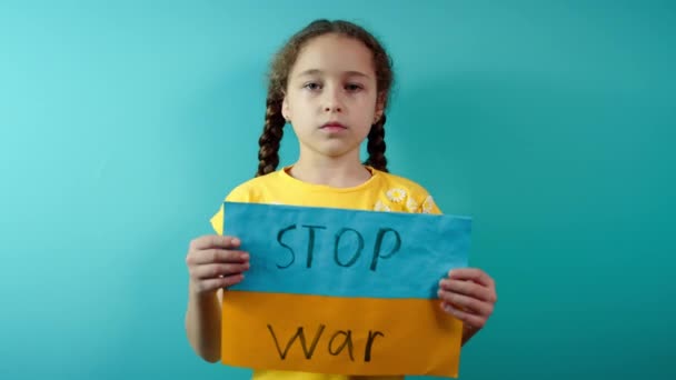 Molesto ucraniano pobre niño asustado niña sin hogar protestar conflicto de guerra levanta pancarta con texto de masaje inscripción No War on blue background. Paz, detener la agresión, niño contra la guerra rusa — Vídeo de stock