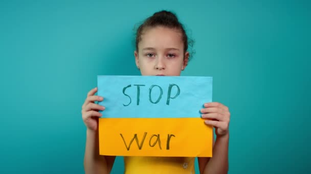 Kesal pada balita Ukraina anak perempuan takut tunawisma memprotes konflik perang mengangkat spanduk dengan tulisan pijat No War di latar belakang biru. Perdamaian, menghentikan agresi, anak terhadap perang Rusia — Stok Video