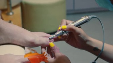 Güzellik uzmanı eski verniği manikür makinesiyle çıkarıyor. Eski jelin çıkarılması. Manikürcü kadın pedikürden önce manikür makinesi kullanarak müşterilerinin tırnaklarındaki jöle parlatıcısını çıkarıyor..