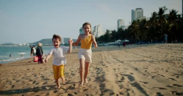 Szczęśliwe dzieciaki biegające po plaży bawiące się z psem, rodzinne wakacje na plaży. szczęśliwy dość kaukaski młody dzieci uśmiech biegając po plaży bawiąc się z ich pies, rodzinne wakacje. — Wideo stockowe