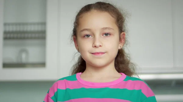 Kanepede oturan güzel yüzlü şirin çocuk portresi. Komik küçük kız kameraya bakarak gülümsüyor. Mutlu çocukluk kavramı.