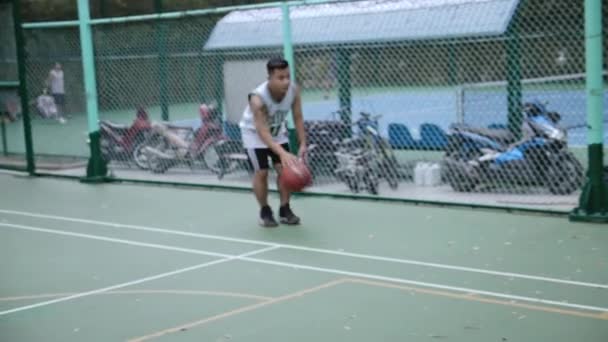 Jugador de baloncesto entrenando en el parque, jugador de baloncesto golpea la pelota, luego lanza la pelota y se pierde el aro y la pelota golpea el aro. Saigón, Vietnam, 6 de abril de 2022 — Vídeos de Stock