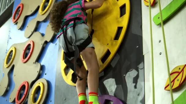 Дитина тренується на скелелазіння. Дитячий альпінізм у приватній школі. Вправи для скелелазіння. Дівчина шкільного віку піднімається на стіну скелелазної стіни . — стокове відео