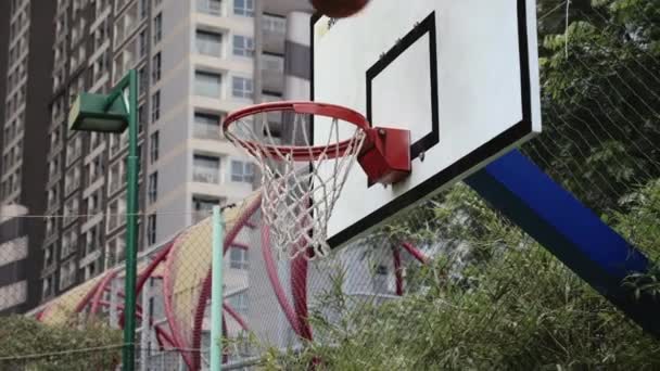 Sport hází do basketbalového koše z různých úhlů. Basketbal prochází basketbalovým košem na basketbalovém hřiště.City mrakodrapy v pozadí. — Stock video