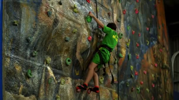 Kind trainiert mit einem Lehrer an der Kletterwand. Kinder klettern in einer Privatschule. Kletterübungen. Ein Junge im Schulalter klettert die Wand hinauf. Saigon, Vietnam, 6. April 2022 — Stockvideo