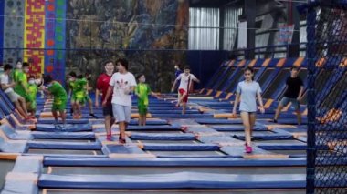 Çocuklar parkta hocalarla atlama eğitimi alıyor. Çocuklar özel okulda kaya tırmanışı yapıyor, tırmanma egzersizleri yapıyor. Okul çağındaki çocuklar bahar tahtalarında jimnastik yapıyor. Saigon, Vietnam, 6 Nisan 2022