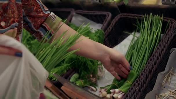 Közelkép Női kéz, fiatal nő háziasszony egy élelmiszerboltban zöldhagymát és élelmiszert vásárol, egy fiatal nő választja a szupermarket élelmiszerosztályán.. — Stock videók