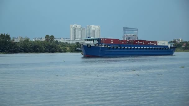 El cargador de carga de transbordadores lleva camiones de carga a lo largo del río Saigón en el centro de la ciudad de Ho Chi Minh, junto al Parque Central Vincom. Saigón, Vietnam, 6 de abril de 2022 — Vídeo de stock