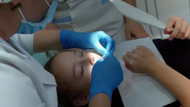 Стоматолог перед удалением, ветер зубной флюгер на молоке маленькой пациентки клиники.Женщина профессиональный стоматолог на рабочем месте. Дантист работает с детьми. Концепция медицины здравоохранения — стоковое видео