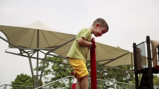 Happy lucu anak ayunan ayunan di taman, anak kecil, ayunan taman bermain pada hari yang cerah, seorang anak ceria mempercepat ayunan ke depan dalam lingkaran, anak tertawa dan tersenyum saat bermain di taman kota. — Stok Video