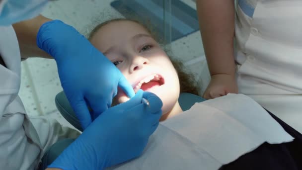 Dentystka bada dziecięce zęby pacjentki w klinice. Zawodowy dentysta w pracy. Koncepcja badania dentystycznego. Dentysta z dziećmi. Koncepcja opieki zdrowotnej i medycyny. — Wideo stockowe