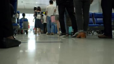 Ho Chi Minh Havalimanı, Asya, Saigon, Vietnam, 10 Nisan 2022 'de uçuşu kontrol etmek için sırada bekleyen bavullarla insanların bacaklarının alçak açılı görüntüsü. Coronavirüs 'ten gelen tıbbi maskeli insanlar