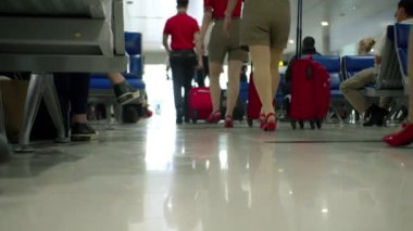 Uçuş görevlilerinin ve valizli hosteslerin alçak açılı görüntüleri havaalanındaki kayıt alanında toplanıyor. Coronavirüs yüzünden tıbbi maske takan insanlar.