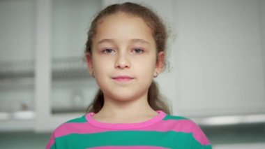Portre güzel yüzlü küçük kız. Komik şirin çocuk gülümseyen çocuk kameraya bakıyor evde kanepede oturuyor..