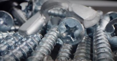 Tahtayı vidayla delmeye çok yakın. Makro vidaları, vidaları, cıvataları, cıvataları, metal yayları ve bir yığın bağlayıcıyı kapatır. Makro için vida kavramı, çelik vidalar.