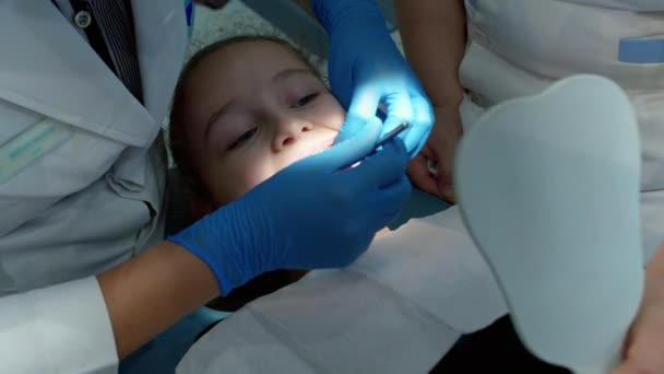 Женщина-дантист осматривает молочные зубы малышки-пациентки в клинике. Женщина-профессиональный дантист на работе. Концепция стоматологического исследования. Работа стоматологом с детьми. Концепция здравоохранения и медицины. — стоковое видео