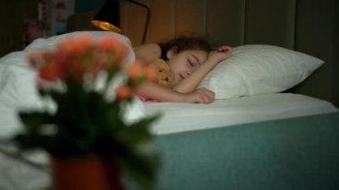 Uyuyan küçük çocuk küçük kız mutlu ve kaygısız yatakta oyuncak ayıya sarılıyor. Bir baba çocuğunu battaniyeyle örter. Uykuda mutluluk.