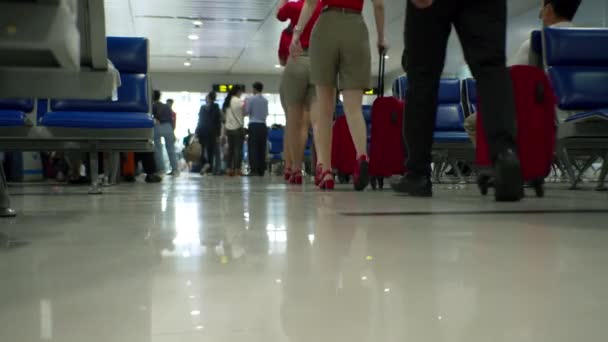 Niski kąt ujęcia stewardów i stewardessów z walizkami maszerujących w formacji wewnątrz strefy odprawy na lotnisku. Osoby noszące maski medyczne od koronawirusa — Wideo stockowe