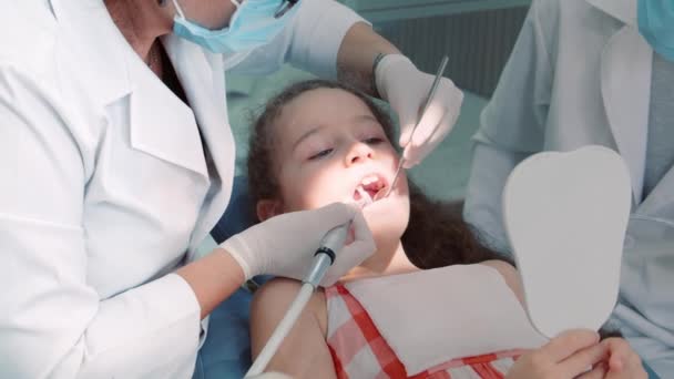 Dentista en el consultorio dental, Mujer Dentista Tratando Dientes a Niña Paciente en Clínica. Doctora Profesional Estomatóloga en el Trabajo. Concepto Dental Check Up. — Vídeos de Stock