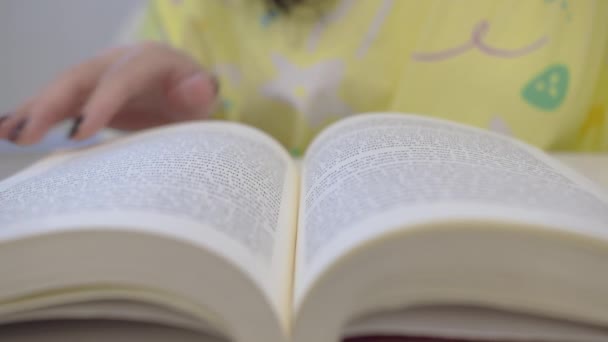 Die Seiten eines Buches von Hand blättern, SCHLIESSEN. SLOW MOTION. Unerkennbare Personen lesen ein Buch und halten die Finger an den Linien entlang. Filmlicht zu Hause oder in der Bibliothek. — Stockvideo