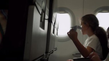 Çocuk uçak penceresinde oturuyor ve uçakta uçarken küçük kağıt uçakla oynuyor. Childs 'ın eli uçak penceresinin arka planında küçük kağıt uçakla.