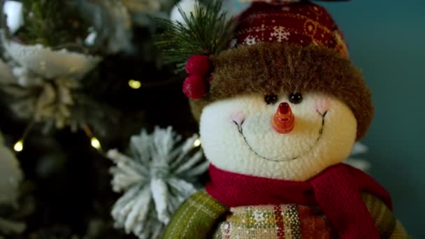 Vue de derrière un bonhomme de neige.Gros plan d'un sapin de Noël décoré avec des boules sur fond de lumières festives lumineuses. Gros plan d'un bonhomme de neige intelligent. Détails des décorations de Noël. — Video