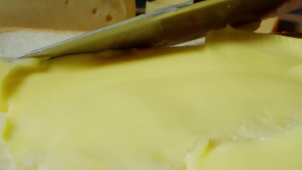 Nůž nanáší máslo na kousek chleba, zblízka. Koncept snídaně nebo oběda - 4K záběry. — Stock video