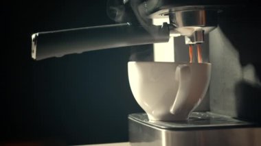 Kahve makinesinden fincana kahve dökülüyor. Ev yapımı sıcak Espresso. Filtre tutacağı kullanılıyor. Taze kahve akıyor. Sabahları kavrulmuş sade kahve içmek.