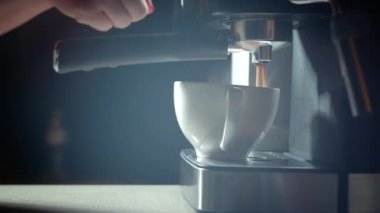 Kahve makinesinden fincana kahve dökülüyor. Ev yapımı sıcak Espresso. Filtre tutacağı kullanılıyor. Taze kahve akıyor. Sabahları kavrulmuş sade kahve içmek.