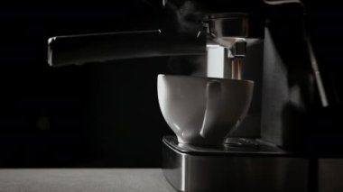 Kahve makinesinden fincana kahve dökülüyor. Ev yapımı sıcak Espresso. Filtre tutacağı kullanılıyor. Taze kahve akıyor. Sabahları kavrulmuş sade kahve içmek.