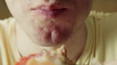 Dişlerinde diş teli olan bir kadının açgözlülükle hamburgerini ısırması, bir restoranda hamburger yemesi, lezzetli bir burgerin tadını çıkarması, iştah açıcı bir şekilde bir burgeri ısırması. 4k.