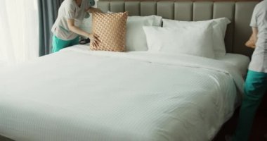 Çalışanlar, otelin iki hizmetçisi, müşteri odasındaki yatağı profesyonel olarak hazırlıyorlar. Beş yıldızlı otel konsepti ve kaliteli oda servisi. Kadınlar odadaki çarşafları değiştiriyor.