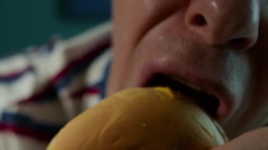 Dişlerinde diş teli olan bir kadının açgözlülükle hamburgerini ısırması, bir restoranda hamburger yemesi, lezzetli bir burgerin tadını çıkarması, iştah açıcı bir şekilde bir burgeri ısırması. 4k.
