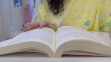 Kitabın El Çevirme Sayfaları, Kapatın. Yavaş bir hareket yap. Tanınmayan İnsanlar El bir kitap okuyor ve parmaklarını çizgiler boyunca tutuyor. Evde veya kütüphanede sinematik ışık.