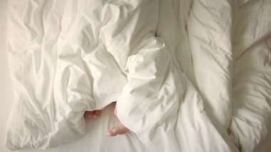 Çerçevede sadece bacaklar var. Aşık bir çift yatakta eğleniyor, ayaklarını farklı yönlere çeviriyor. Evlilik, aile, aşk. Evlilik, aile, aşk, seks konsepti. Sabah 4-K 'da..