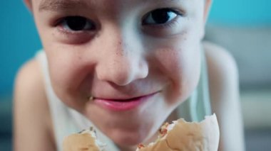 Little boy in fast food cafe eats burger. Portrait of hungry child Cute little kid eating burger. Hungry child in fast food cafe. Close-up boy eating burger. Hungry child in cafe. Lovely boy