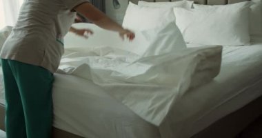 Çalışanlar, otelin iki hizmetçisi, müşteri odasındaki yatağı profesyonel olarak hazırlıyorlar. Beş yıldızlı otel konsepti ve kaliteli oda servisi. Kadınlar odadaki çarşafları değiştiriyor.