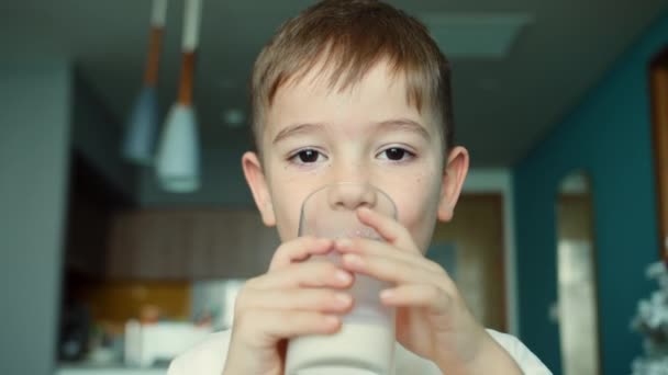 子供のミルクを飲んでる 子供が朝食を食べるのは健康な子供の夢の概念 台所の娘はヨーグルトミルクを飲んでケフィアは唇を舐める 正の子供は朝食を食べ — ストック動画