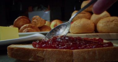 Tereyağlı ve reçelli sandviç. Bir parça ekmek tostunun üzerine ahududu reçeli döken kaşık. Tatlı reçelli sandviç. Sabahları mutfakta nefis kahvaltı hazırlıyorum. Tatlı, lezzetli, fast food.