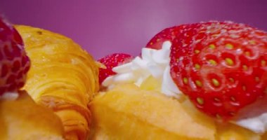 Kremalı ve çilekli donutlar koyu pembe arka planda, makro lensler tatlı tatlılar arasından geçiyor, ilginç düşük perspektifli..