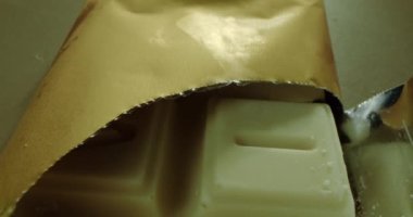 Açık bir kutuda, üzerinde Latince harfler olan turuncu çikolata parçalarının olduğu bir tramvayın makro yan görüntüsü. Çikolatalı şekerler. Bütün bölgeyi dolduran çikolatalar. Yaklaştın. Kırmızı, yeşil, sarı, kahverengi