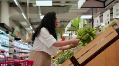 Pembe takım elbiseli çekici genç kadın lahana salatası seçiyor, süpermarketten alışveriş yapıyor, bakkaldan sağlıklı yiyecekler alıyor, marketten lahana salatası alıyor, süpermarketten. Market alışverişi kavramı