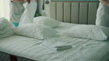 Çalışanlar, otelin iki hizmetçisi, müşteri odasındaki yatağı profesyonel olarak hazırlıyorlar. Beş yıldızlı otel konsepti ve kaliteli oda servisi. Kadınlar odadaki çarşafları değiştiriyor.