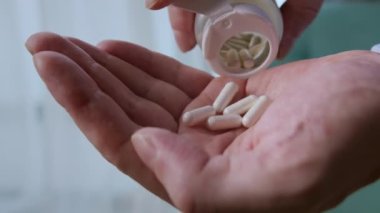 Yaşlı yetişkin bir adam, elinde erkek eline ağrı kesici hapları tutarak ilaç şişesinden iki kapsül dolduruyor, yaşlı büyükanne sağlık hizmetleri, eczane ve tedavi konsepti, yakın görüş..