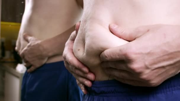 脂肪男性腹 セルライトをチェックするために皮膚を保持男 脂ののった腹の上の毛むくじゃらの皮膚 灰色の背景のプラスチック手術の概念 — ストック動画